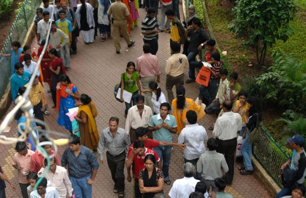 A group of college students and parents gather to review their exam results at Khalasa College in Mumbai, India. 